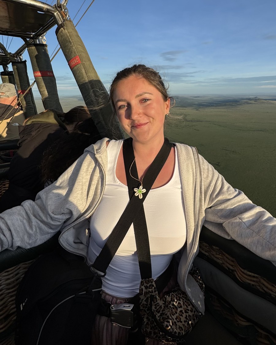 Abbie Stratford, founder of MFL Made Simple, smiling in the basket of a hot air balloon above open grassland